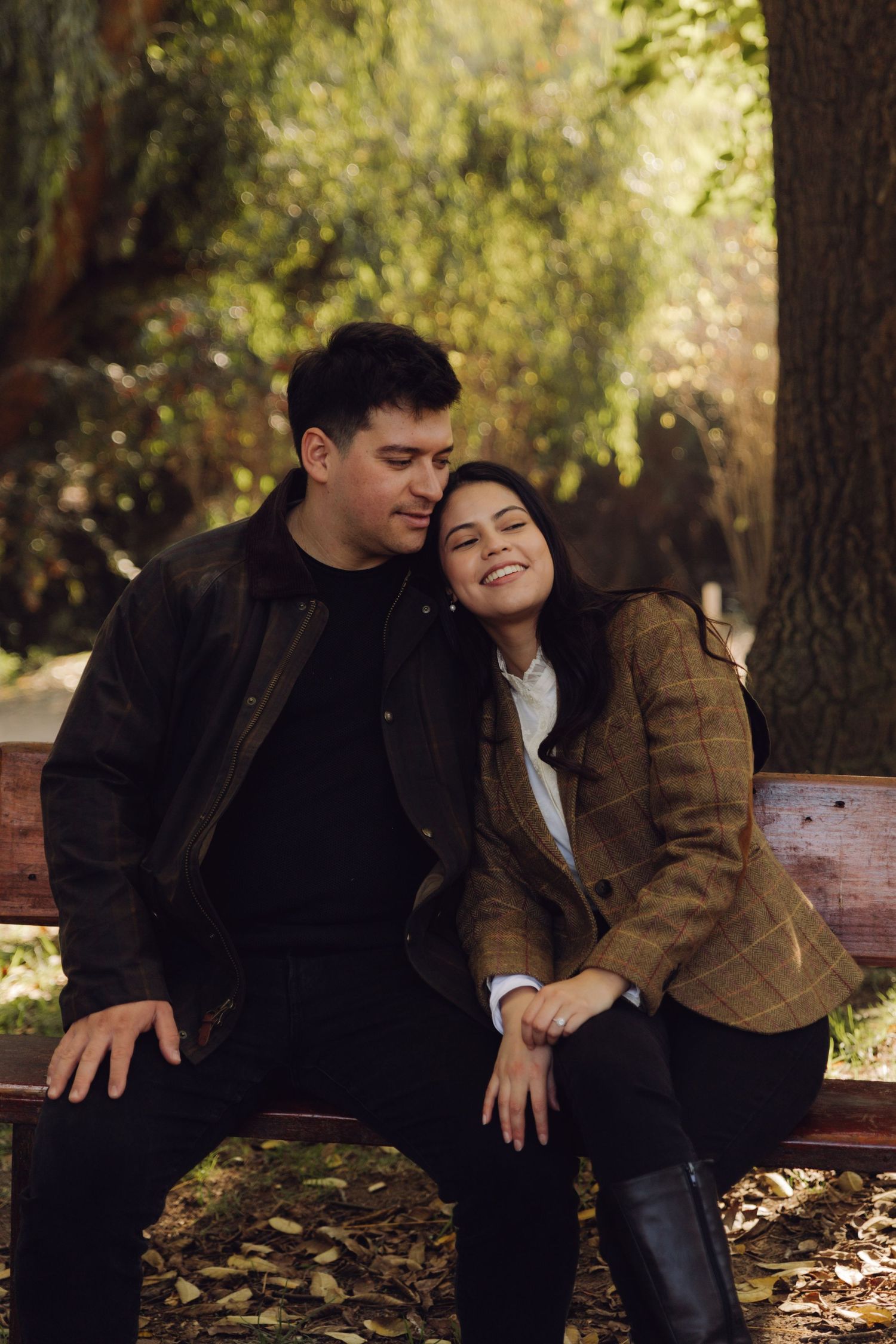 Happy couple cuddling on a wooden bench in a peaceful autumn park setting.