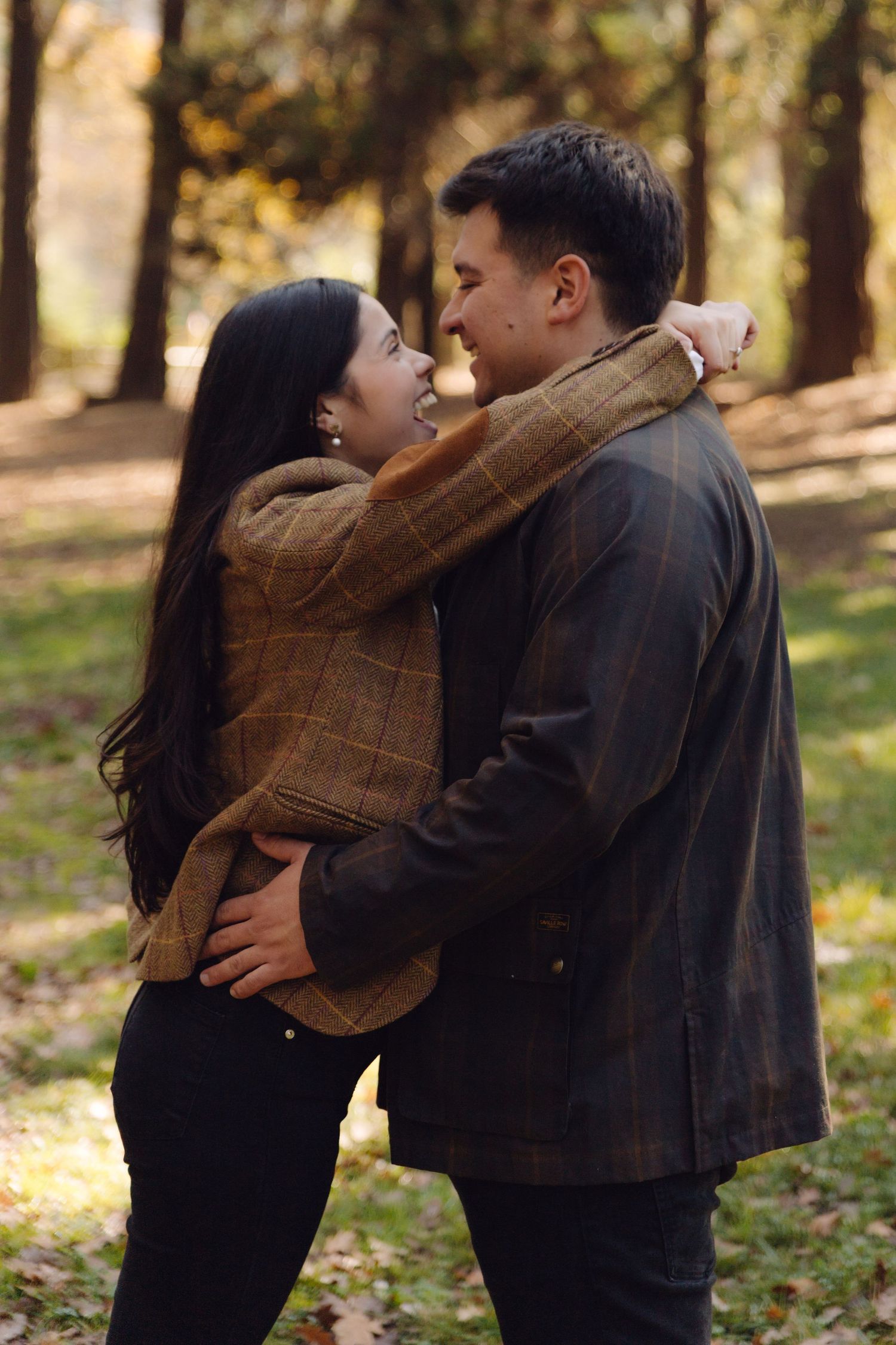 Smiling couple embracing face to face in a beautiful autumn park with golden trees in background.