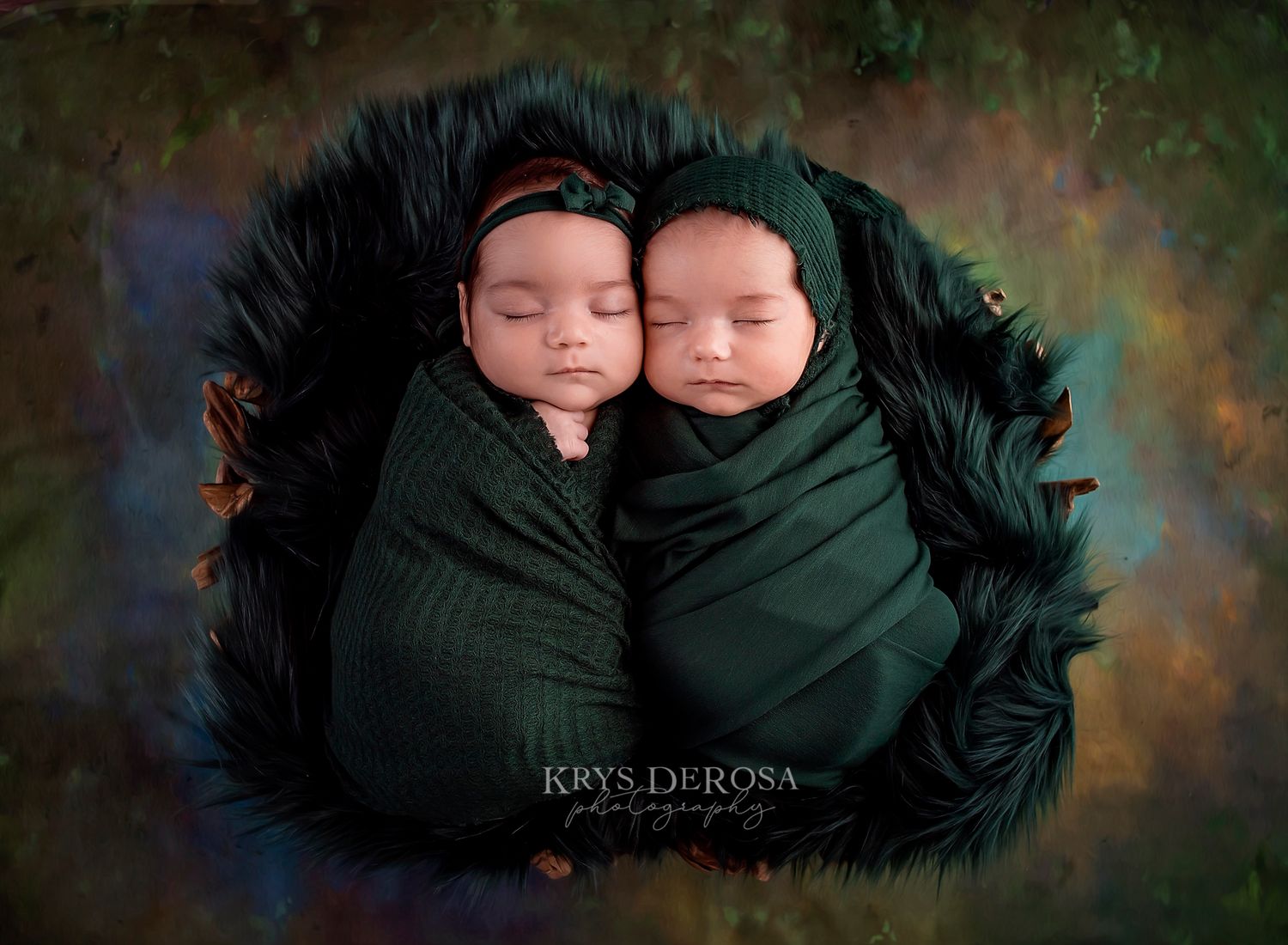 Two newborn twins swaddled in green wraps sleep peacefully in a dark fur-lined bowl by Krys DeRosa Photography.