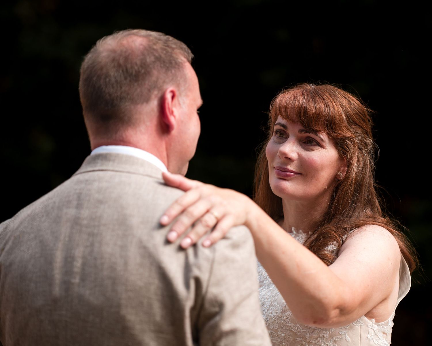 Bride gazing lovingly at groom during first dance at outdoor wedding ceremony.