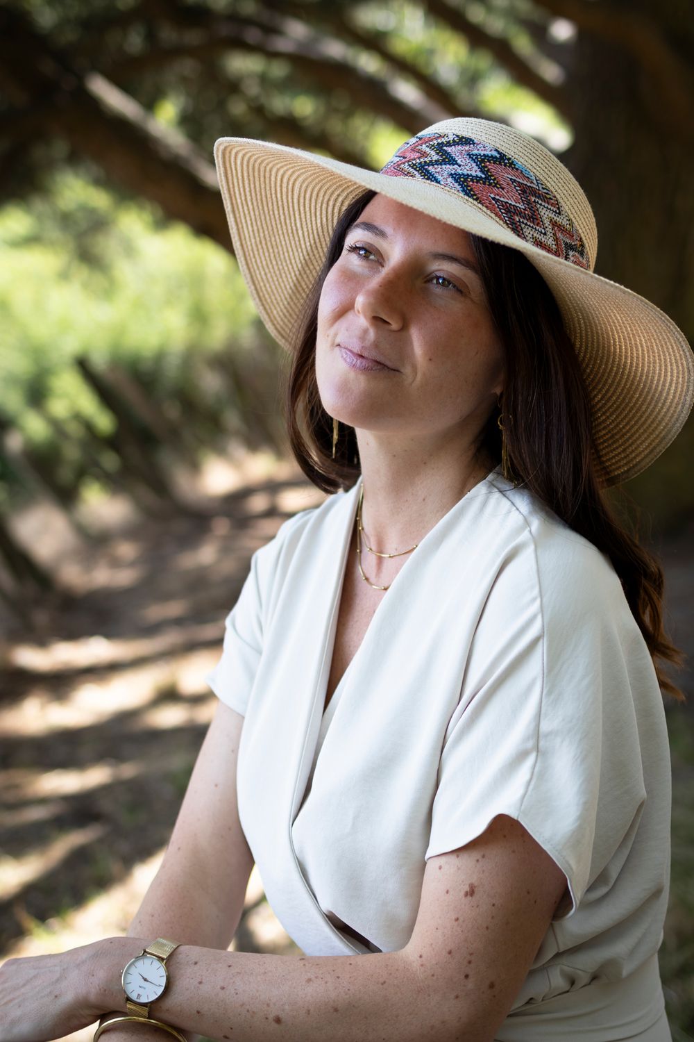 Portrait d’une femme au chapeau de paille, assise sous les arbres en robe blanche, séance à Lyon