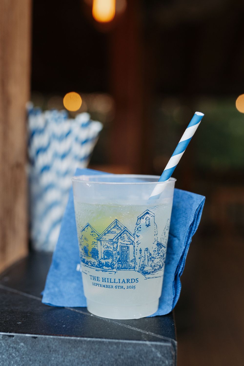 Custom frosted cup printed with The Hilliards September 6th, 2025, featuring a blue striped straw on a blue napkin.
