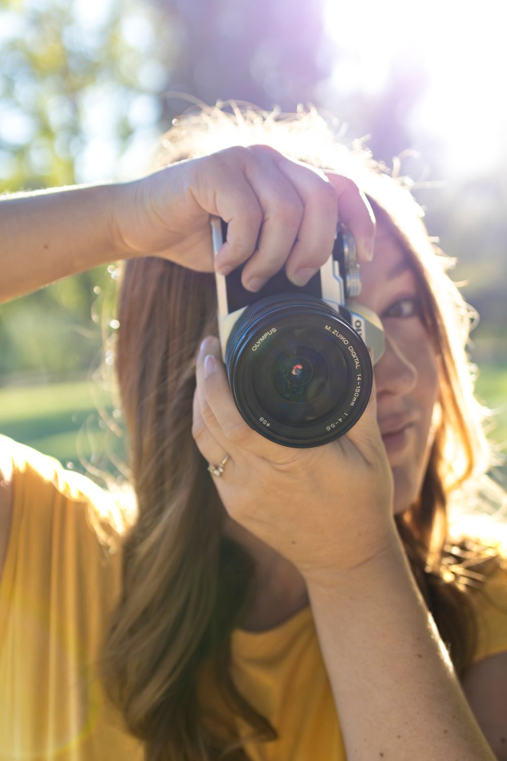 Jade, photographe, le visage caché derrière son appareil photo à contre-jour, séance en Savoie