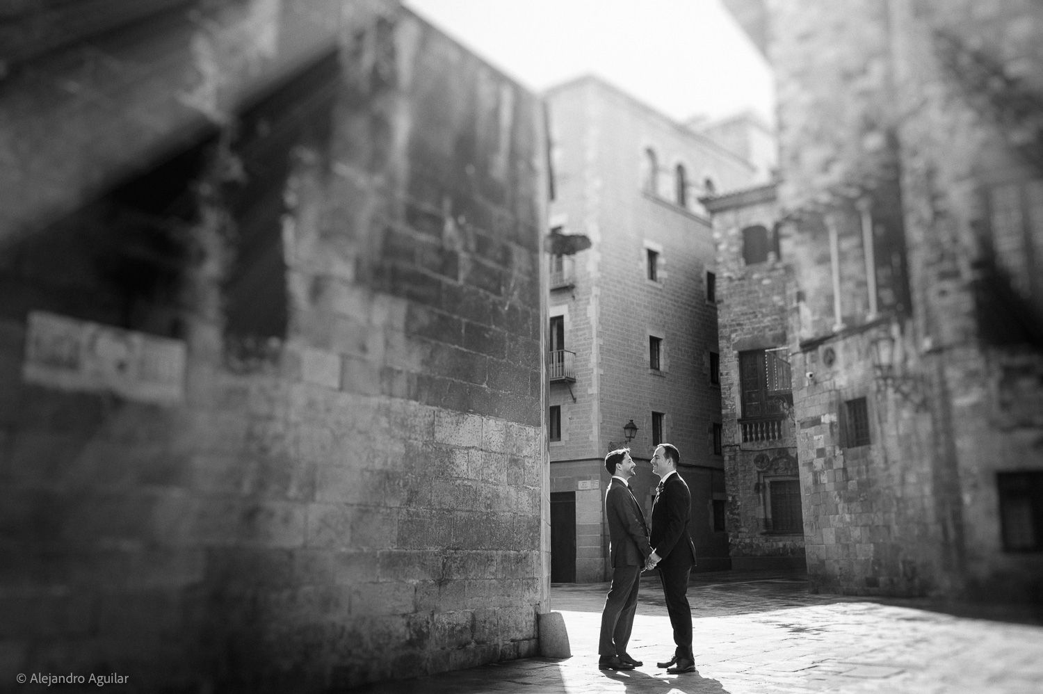 Black and white photo of two men in suits standing face to face in a sunlit European courtyard.
