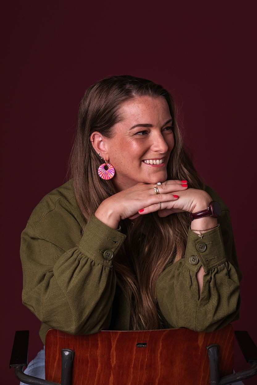 Studio portretshoot voor zakelijke fotografie met een donkerroze achtergrond met vrouwelijke creatieve ondernemer.