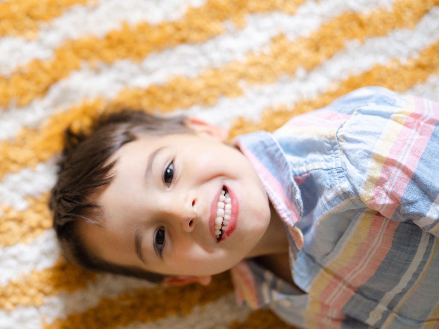 Close up of brother laying on a sunshine rug during his sister's newborn photos in nj.