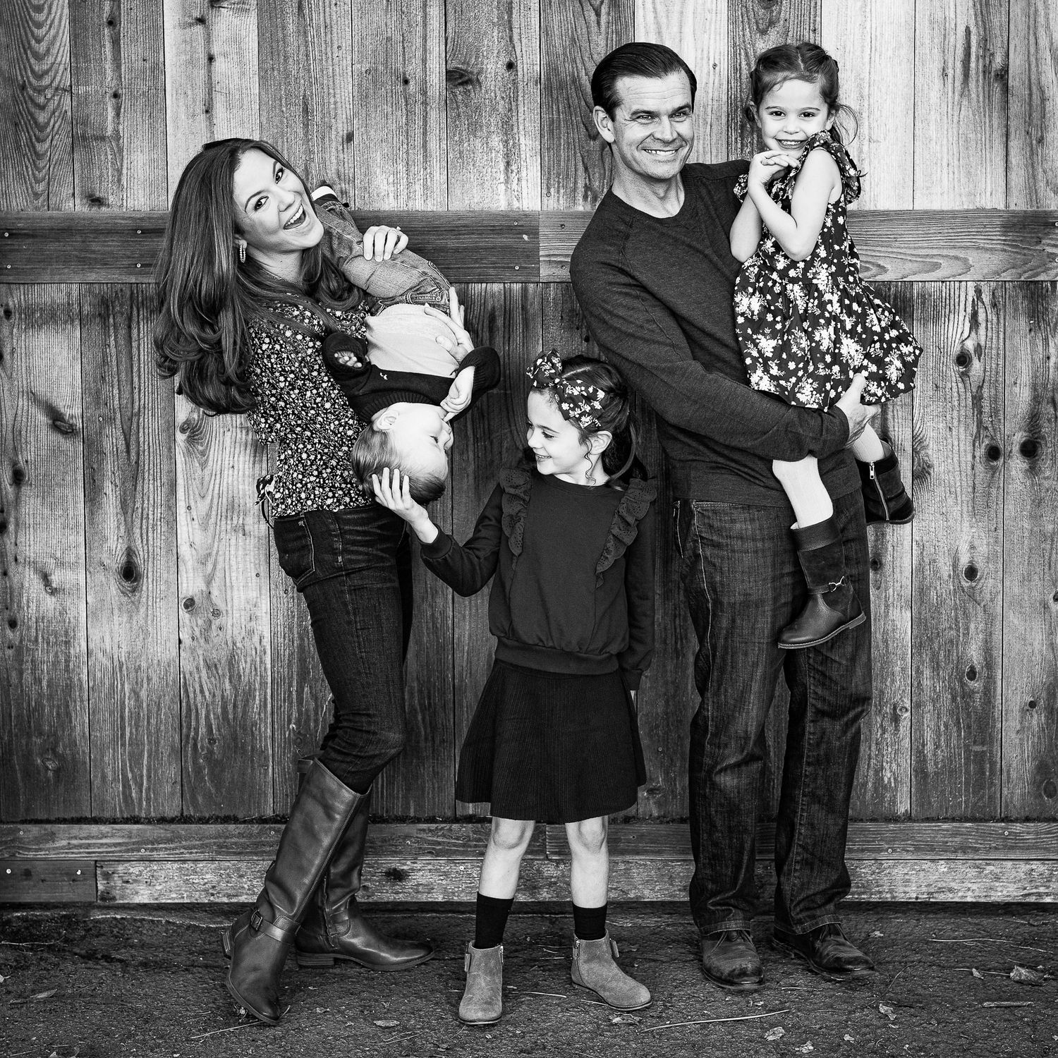 Black and white portrait of a young couple smiling and holding their newborn baby together.