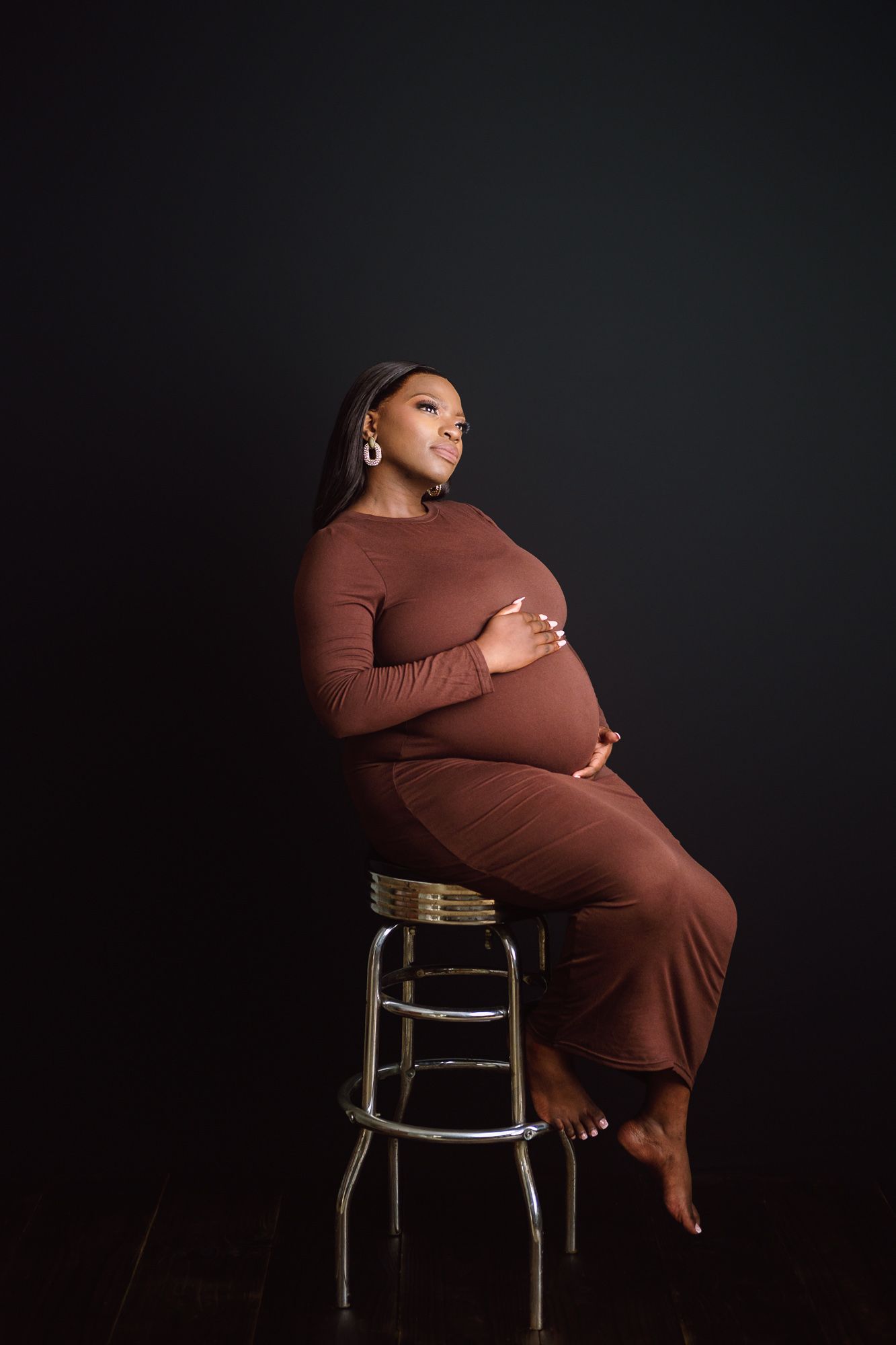 Pregnant mother sitting on a chair during an elegant studio maternity photoshoot