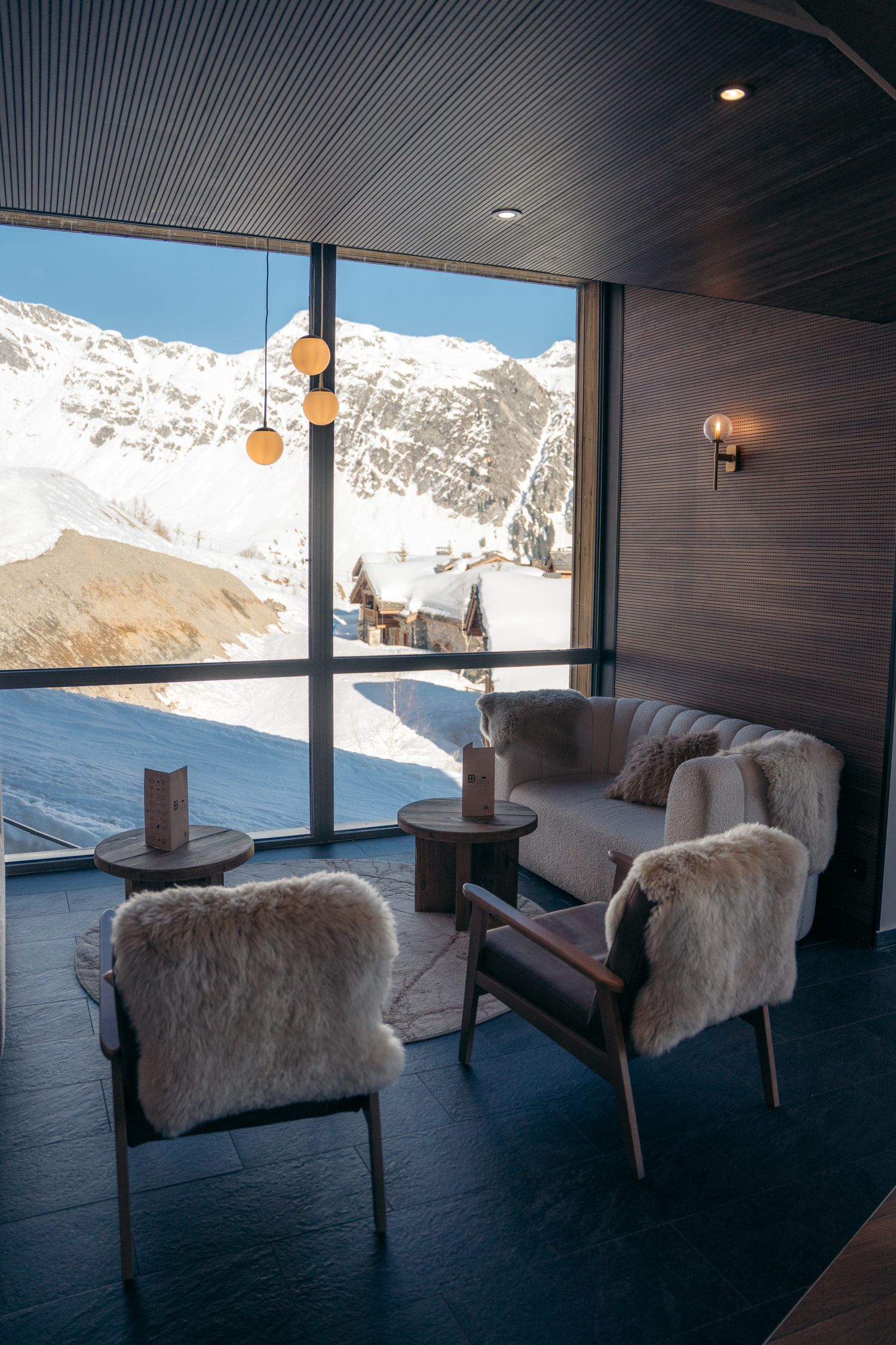 salon résidence odalys l'ecrin blanc de la rosière avec montagnes enneigées derrière la vitre