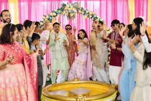 Joyful Indian wedding guests celebrating with the couple under a decorated mandap during ceremonies.