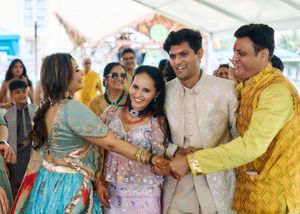 Indian groom sharing a warm moment with smiling family members during a festive wedding celebration.