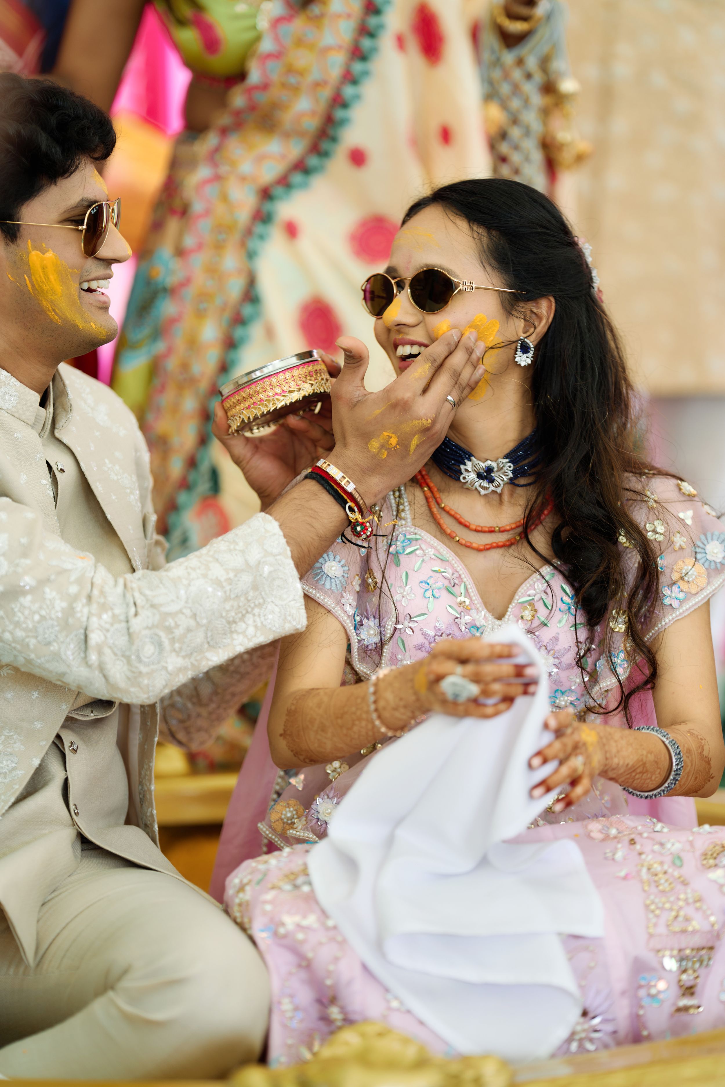 Indian couple applying turmeric to each other during a traditional Haldi wedding ceremony outdoors.