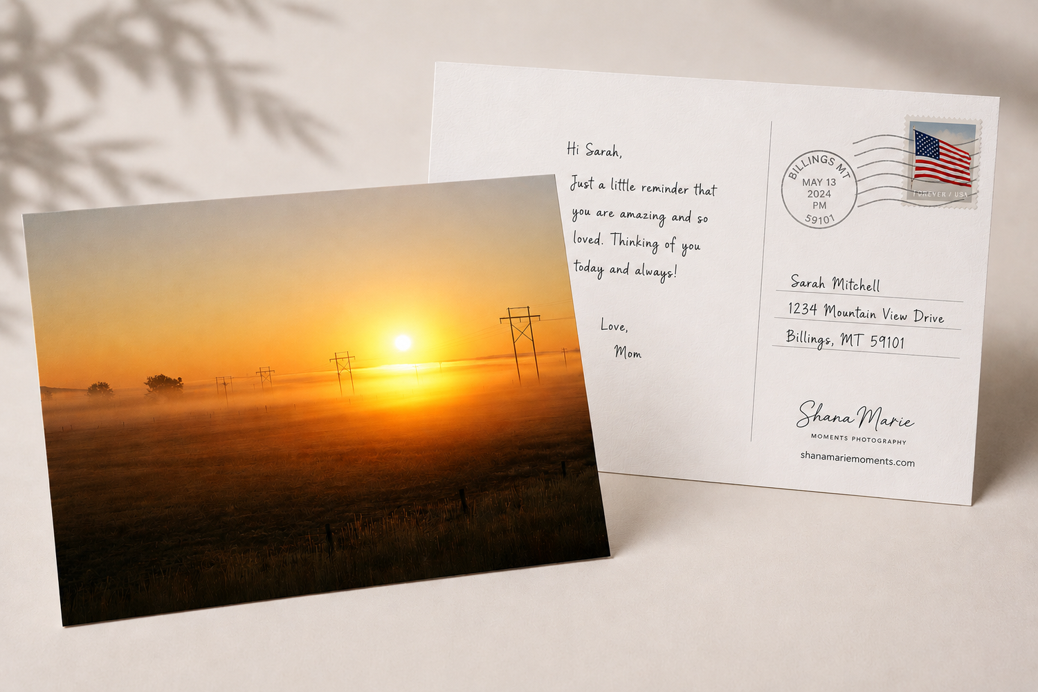 A postcard featuring a scenic foggy sunrise over a rural landscape with power lines, addressed and stamped, ready to mail.