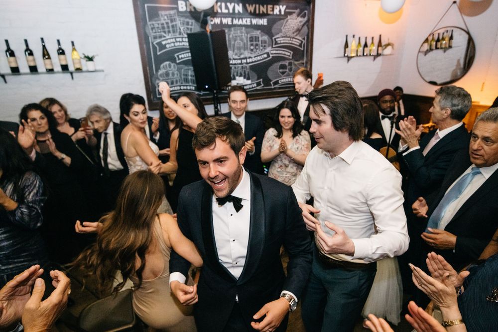 Energetic crowd celebrating at a wedding reception party with disco lights and dancing.