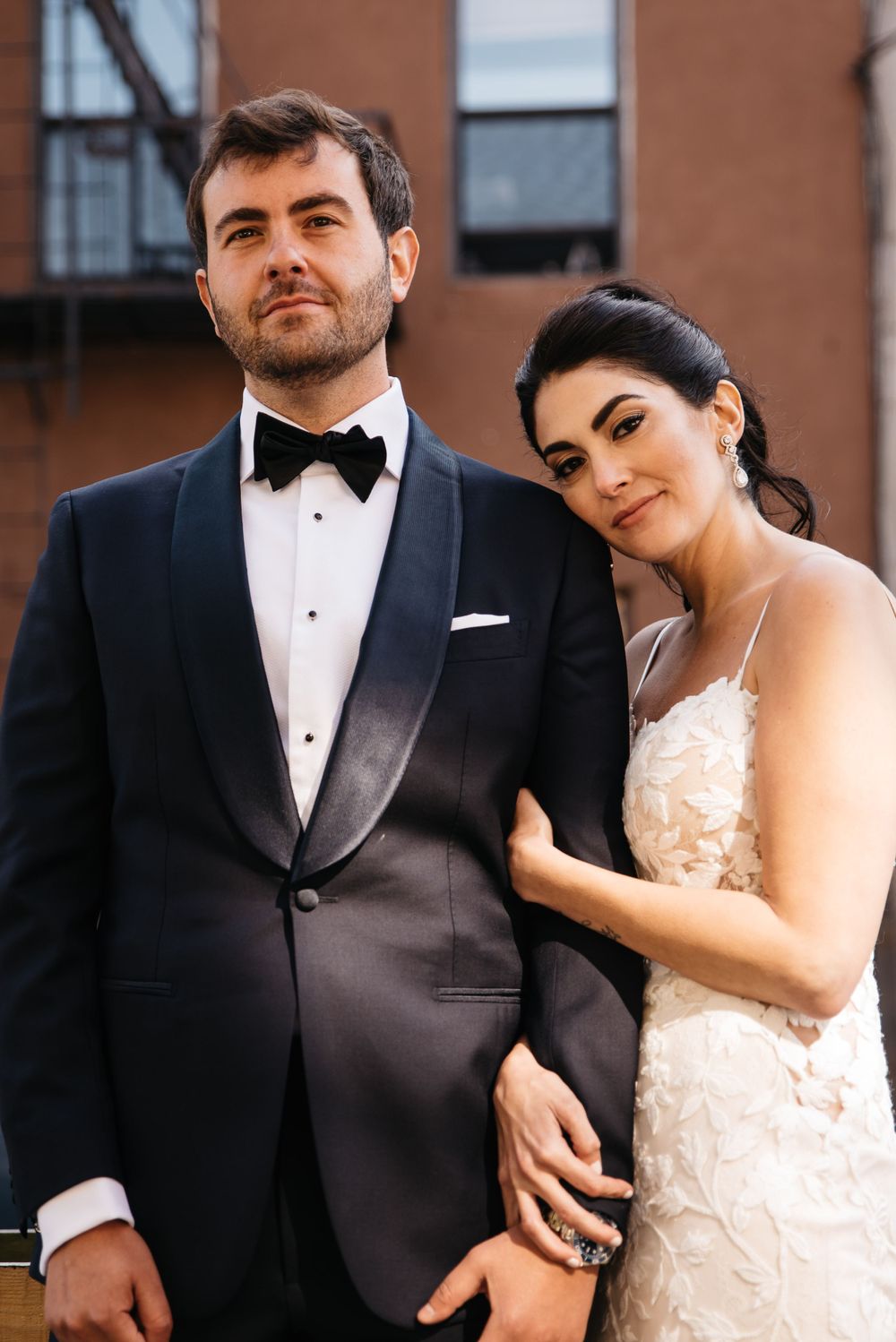 Wedding portrait against brick wall backdrop in formal attire.