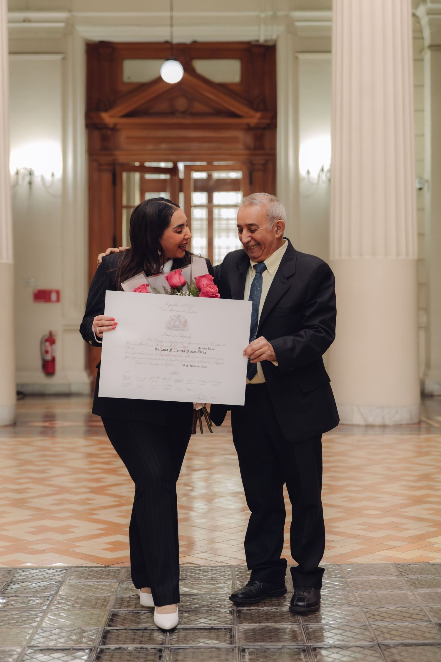 Young woman and elderly man share joyful moment holding graduation diploma.