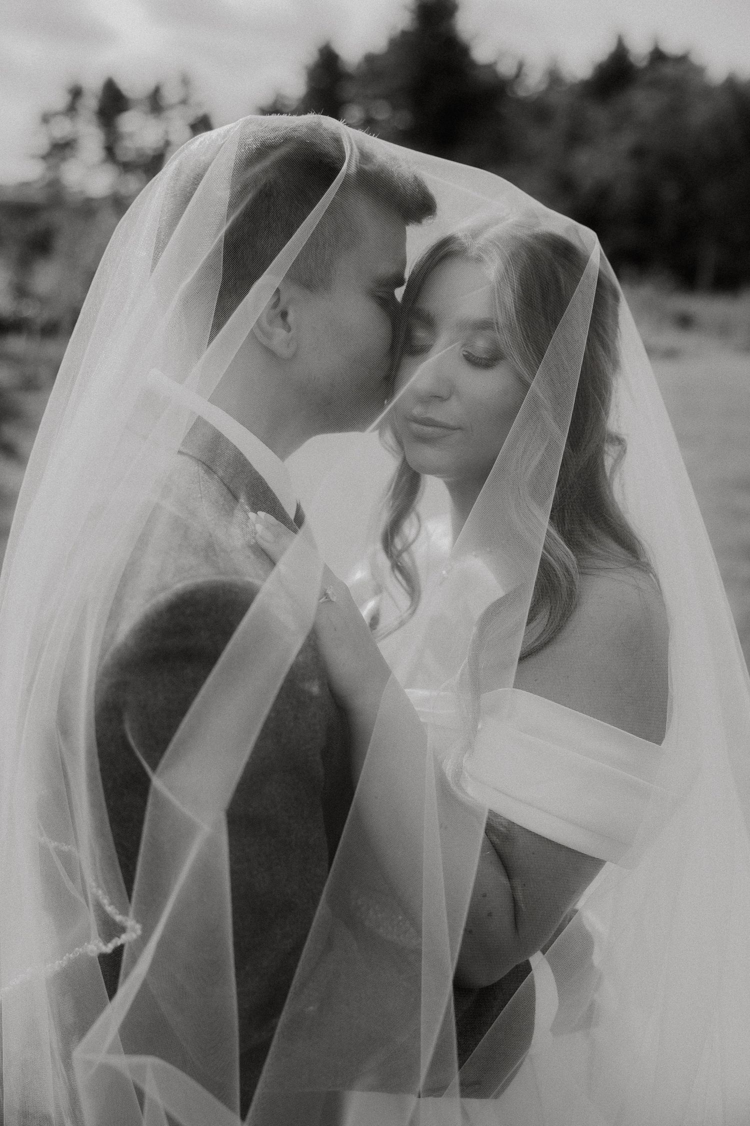 A series of black and white romantic wedding photos showing tender moments between a couple under a flowing veil.