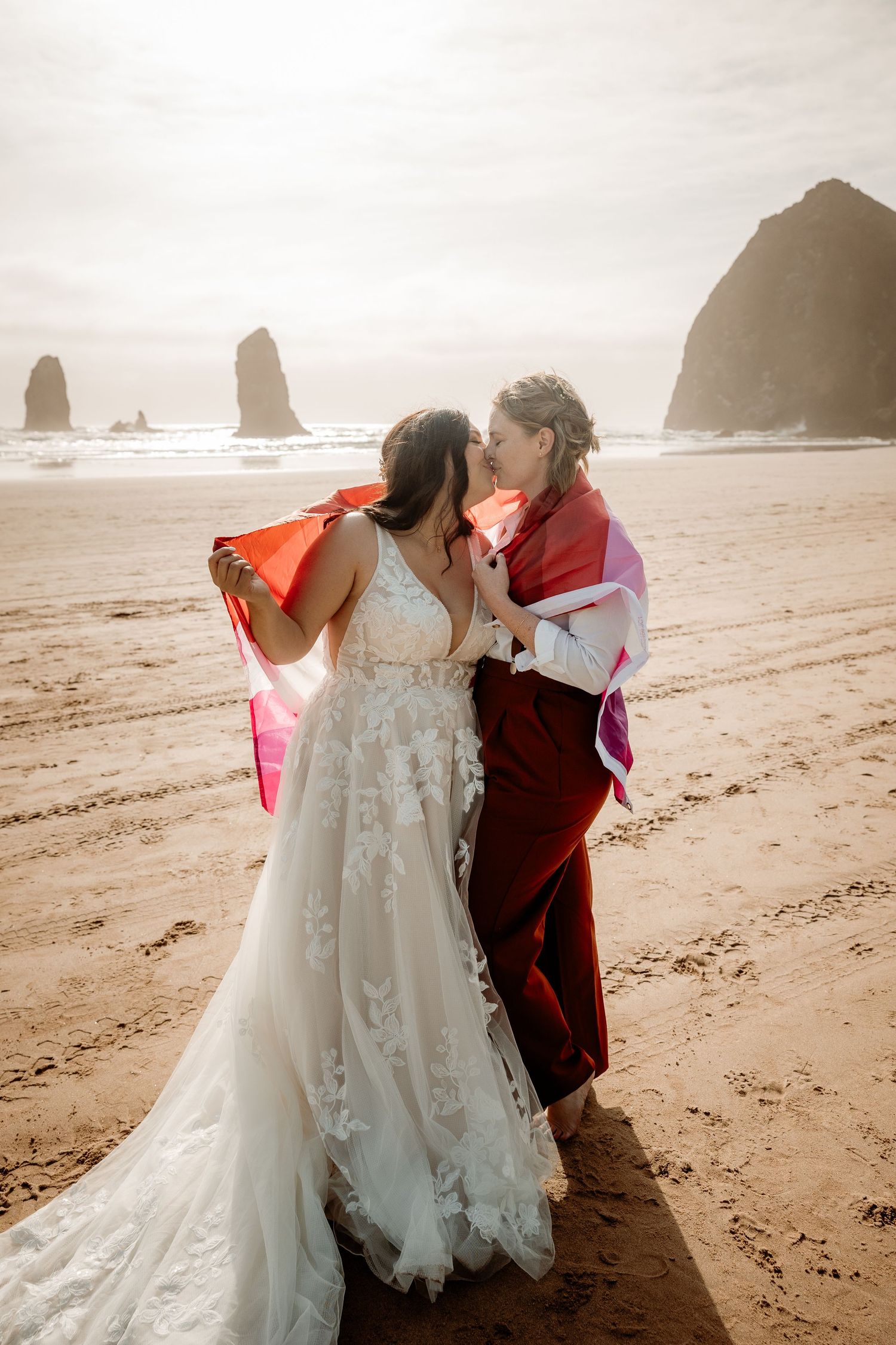 Romantic coastal photoshoot of a couple in wedding attire sharing an intimate moment on a misty Pacific Northwest beach.