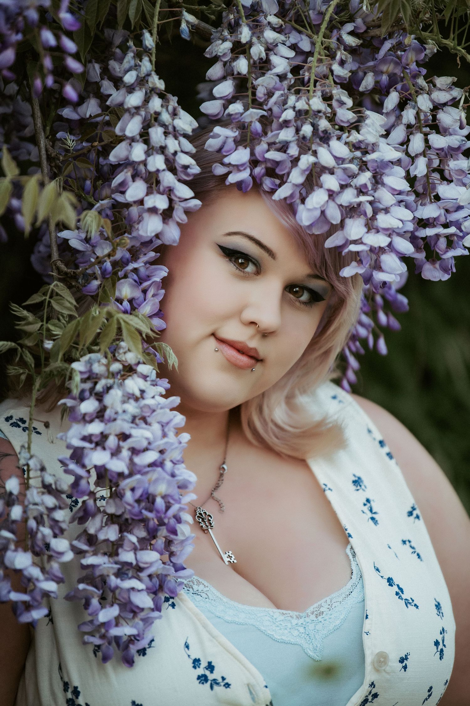 Blooming purple wisteria flowers frame a dreamy spring portrait amidst lush garden foliage.