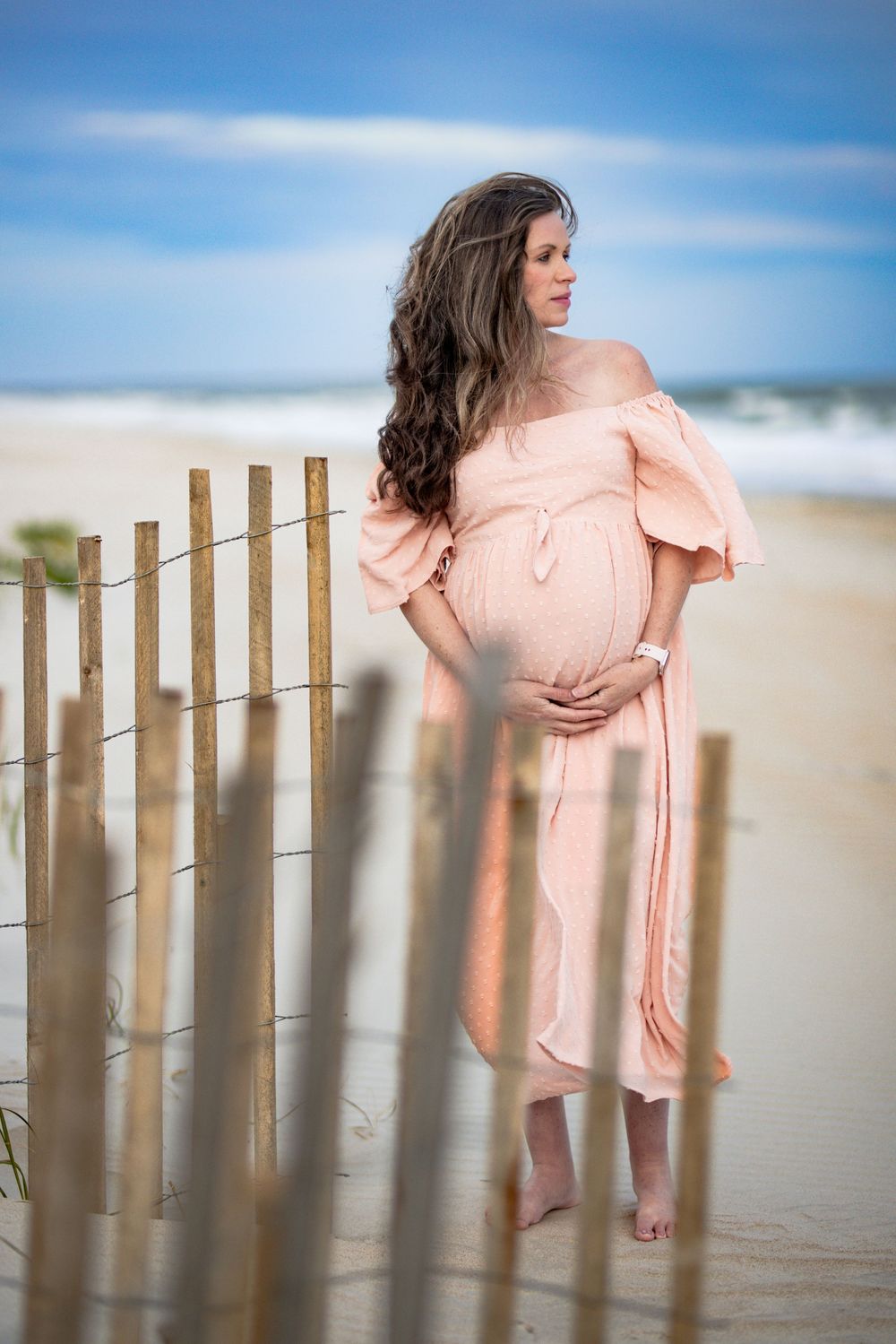Expectant mother in a pink dress at the beach during a destination maternity session in Orange Beach, Alabama