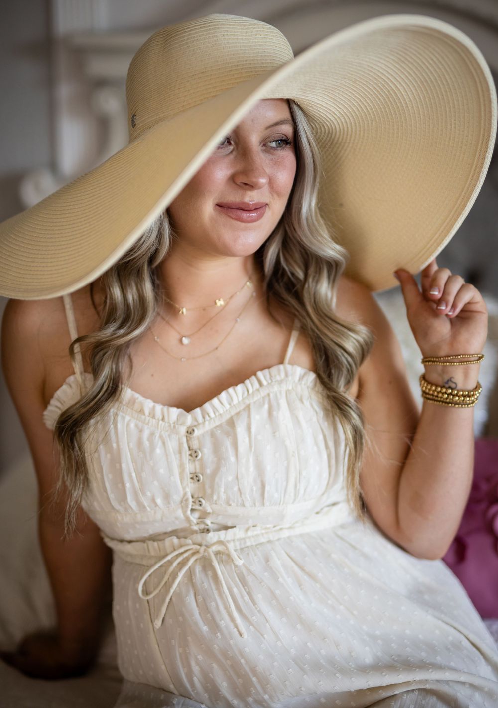 Expectant mother in a white dress and floppy hat during a studio maternity session in Mountain Home, Arkansas