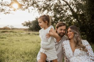 A family enjoying a sunset moment together in a sunlit meadow with trees in the background.