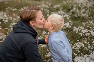 A tender moment captured between a parent and child surrounded by white wildflowers in a field.