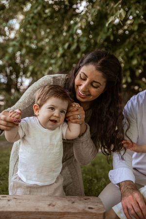 A family shares a joyful outdoor moment together on a sunny day with green foliage in the background.