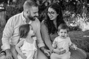 A black and white portrait of a young family sitting together outdoors and sharing sweet moments together.