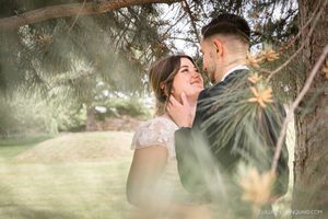 Romantic wedding portraits captured through tree branches in soft natural light.