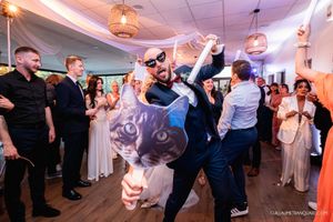 Wedding guests dancing and celebrating at a lively reception with dynamic lighting.