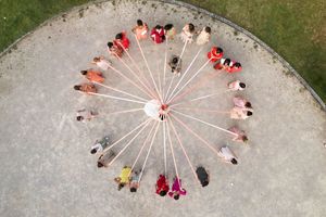 Aerial view of wedding guests arranged in a sunburst pattern on concrete.