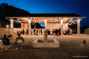 Panoramic twilight view of an outdoor wedding venue with string lights and guests.
