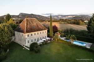 Aerial view of an elegant white manor house with swimming pool and manicured grounds.