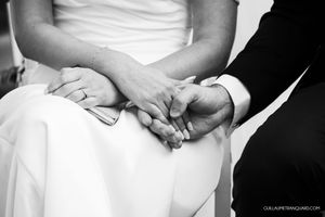 Close-up black and white photo of clasped hands showing wedding rings.