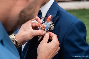 Close-up sequence of pinning a boutonniere on a navy blue suit jacket.