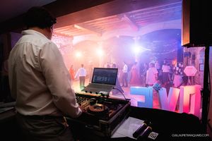 Wedding reception dance floor with dramatic pink lighting and DJ setup in silhouette.