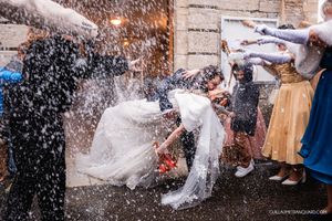 Wedding celebration with champagne spray against a rustic brick wall backdrop.
