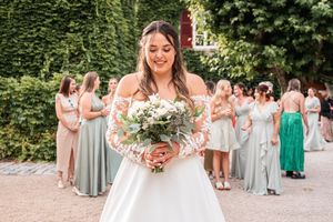 Bridesmaids in pastel dresses gather outdoors for group photos at a wedding.