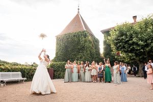 Wedding party posing for photos on a scenic outdoor path with greenery and buildings.