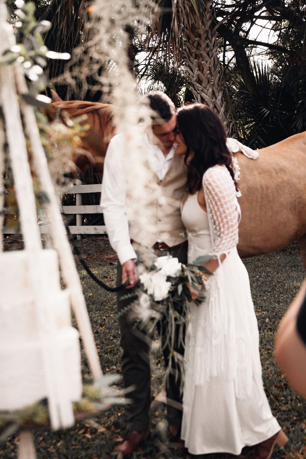 An intimate wedding moment captured outdoors with decorative macrame and a horse nearby. Best Port Saint Lucie Photographer for couples, wed