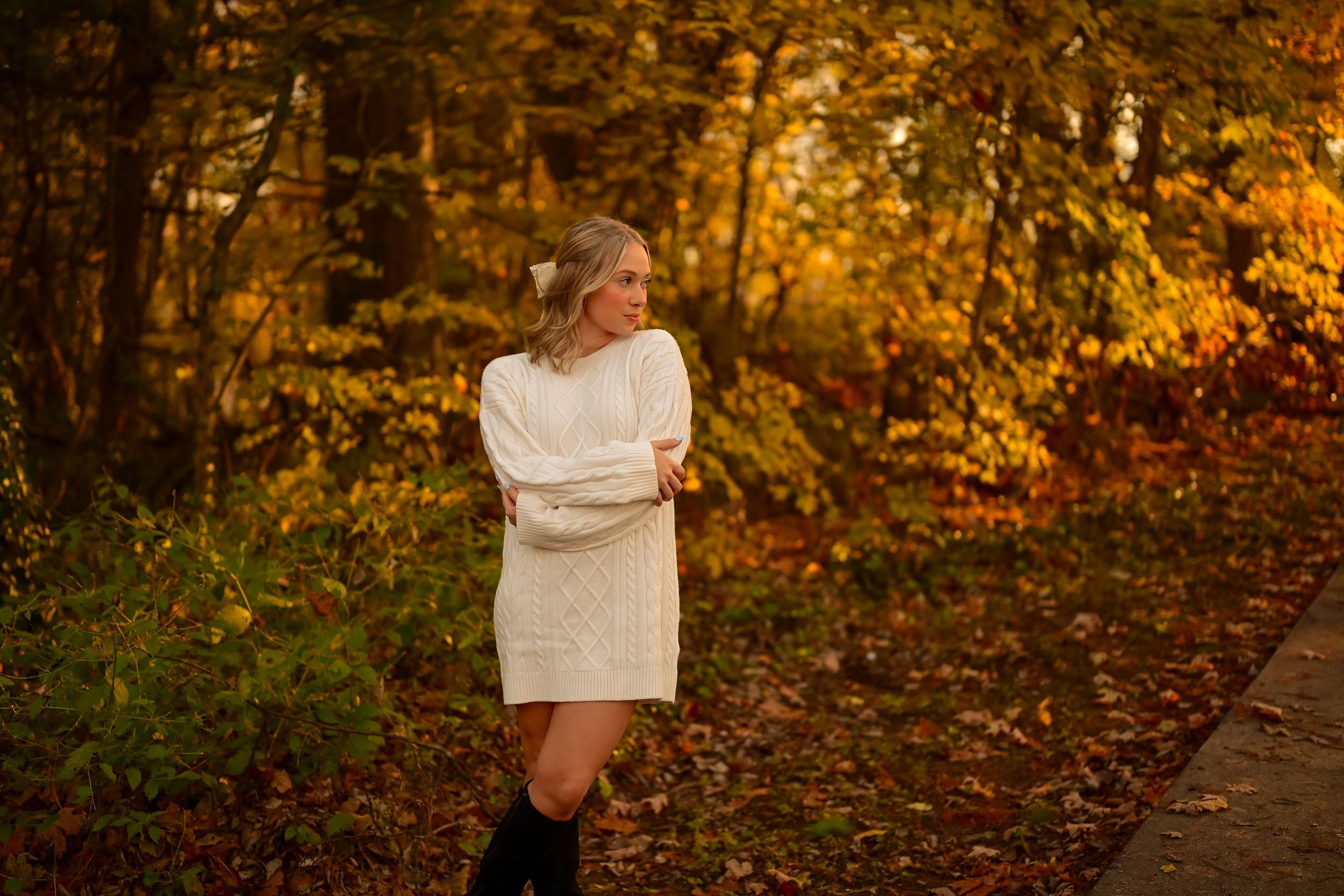A couple shares an intimate moment surrounded by vibrant autumn foliage in a park setting at sunset.