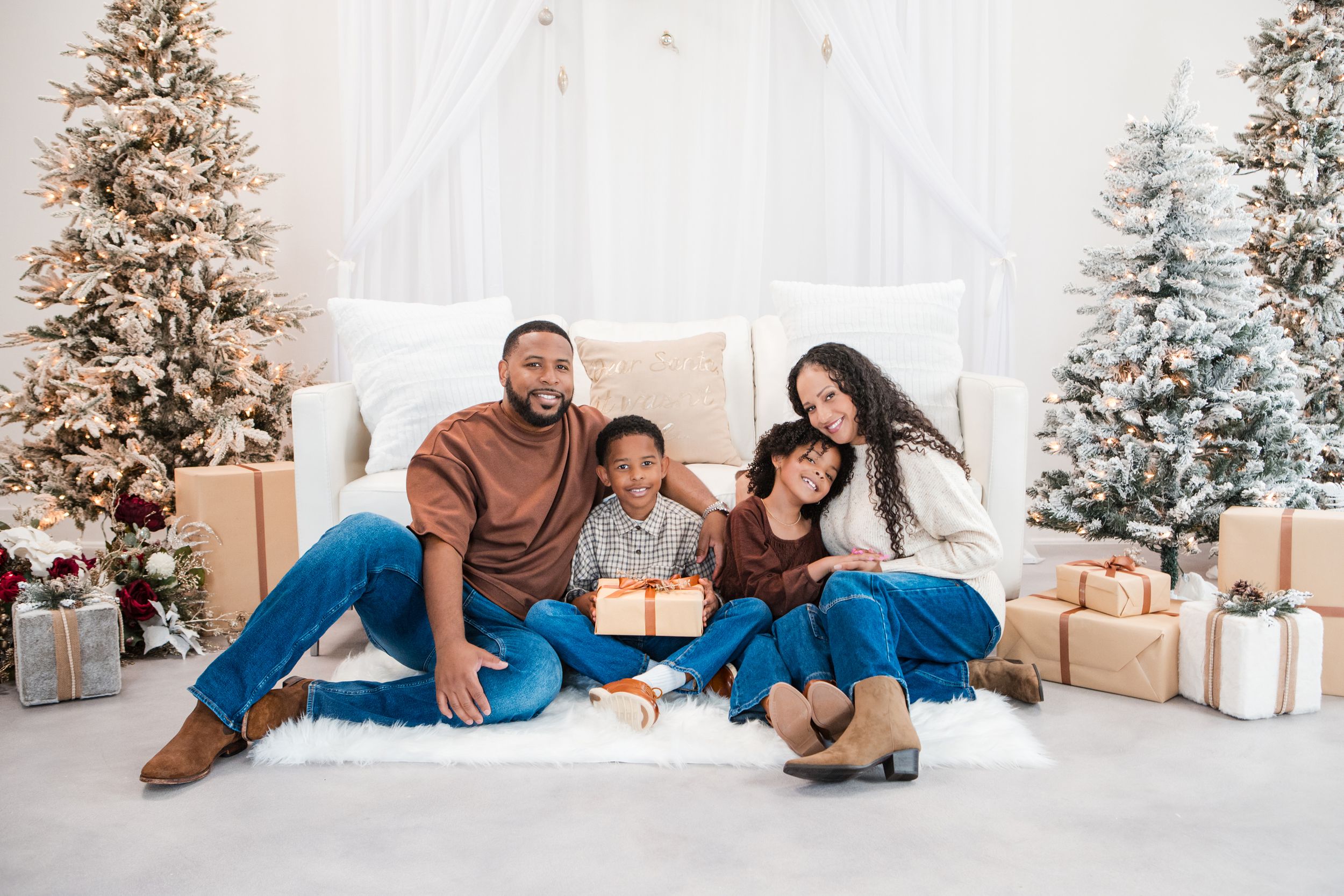 Family in matching blue outfits lying on floor near decorated Christmas tree with presents. Holiday Photoshoot
