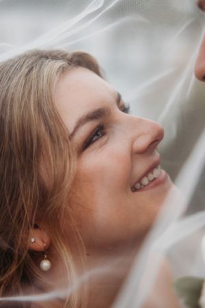 Close-up wedding portrait through delicate veil with soft natural light.