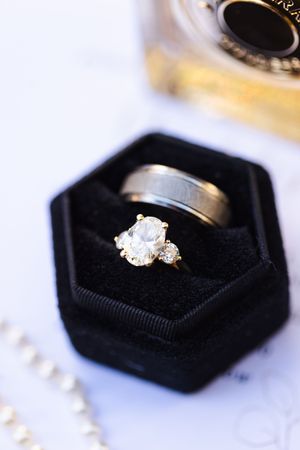 Three elegant diamond engagement rings displayed in black velvet jewelry boxes on a light surface.