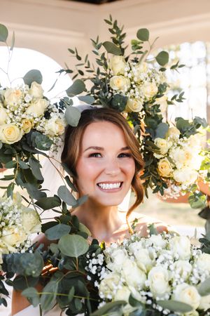 Bridal portrait surrounded by elegant white roses and eucalyptus greenery in natural light.