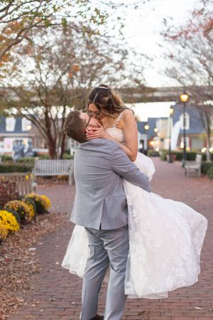 A romantic dip kiss on brick walkway with autumn decorations.