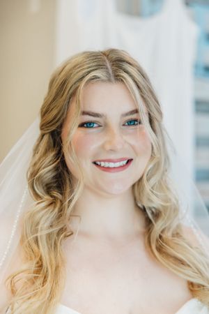 A bridal portrait showcasing soft waves and natural makeup with a delicate veil.