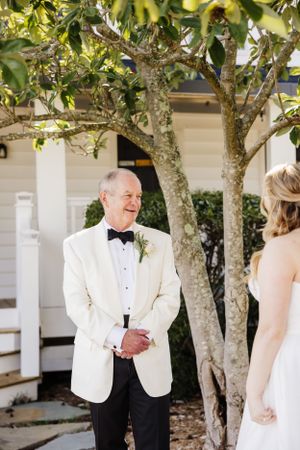 An outdoor wedding first look moment between two people under blooming trees.