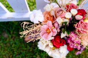 A colorful wedding bouquet with pink, red, and white roses arranged on grass.